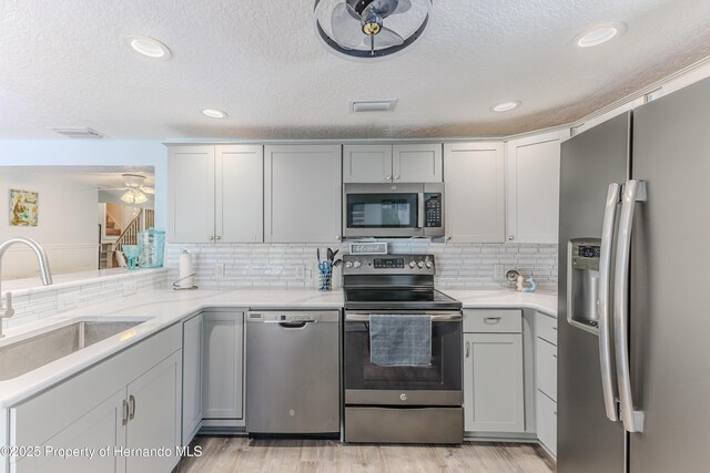 5507 Darlene St, Weeki Wachee, FL 34607 - kitchen featuring stainless steel appliances, a sink, a textured ceiling, light wood-type flooring, and backsplash