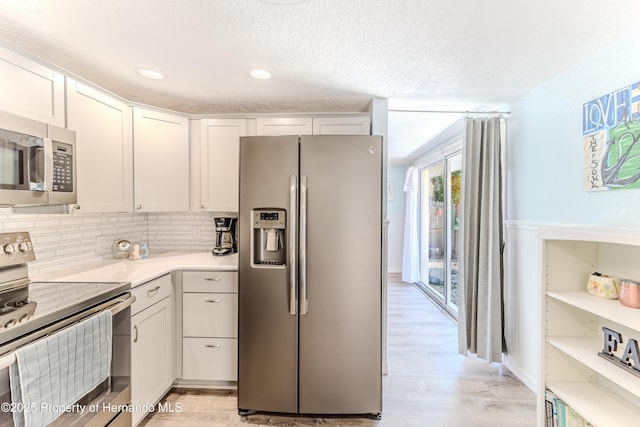 5507 Darlene St, Weeki Wachee, FL 34607 - kitchen featuring appliances with stainless steel finishes, light countertops, decorative backsplash, white cabinetry, and light wood finished floors