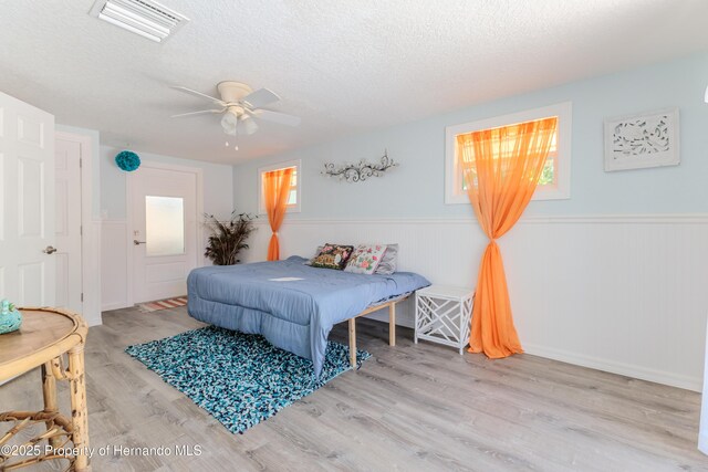 5507 Darlene St, Weeki Wachee, FL 34607 - bedroom with a wainscoted wall, a textured ceiling, wood finished floors, and ceiling fan