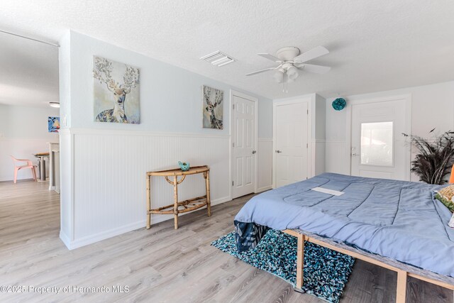 5507 Darlene St, Weeki Wachee, FL 34607 - bedroom featuring wood finished floors, wainscoting, a textured ceiling, and a ceiling fan