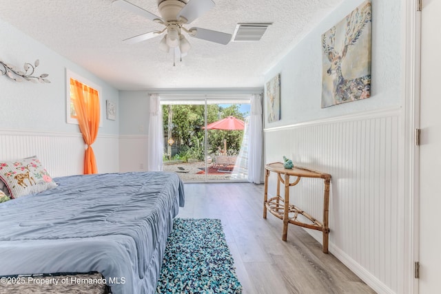 5507 Darlene St, Weeki Wachee, FL 34607 - bedroom featuring a textured ceiling, a wainscoted wall, wood finished floors, access to outside, and ceiling fan