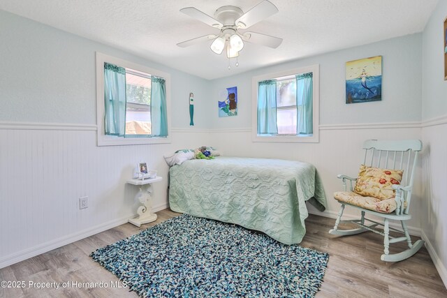 5507 Darlene St, Weeki Wachee, FL 34607 - bedroom with a wainscoted wall, wood finished floors, a ceiling fan, and a textured ceiling