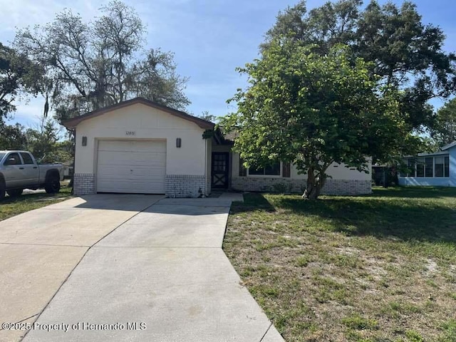 12801 Winding Way, Hudson, FL 34667 - view of front of property with brick siding, an attached garage, driveway, and a front yard