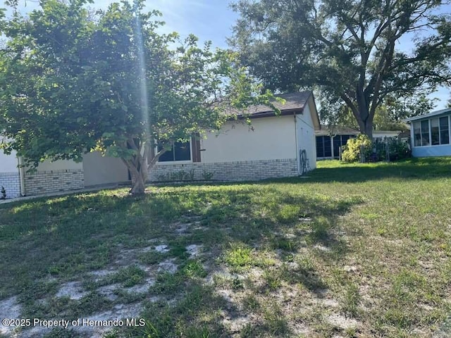 12801 Winding Way, Hudson, FL 34667 - view of home's exterior with brick siding and a yard