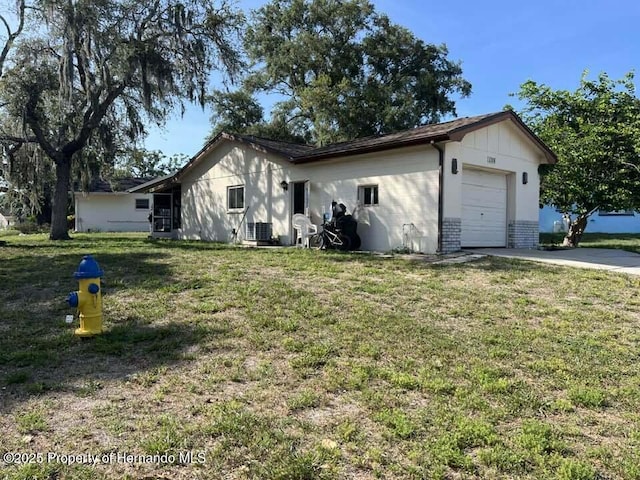 12801 Winding Way, Hudson, FL 34667 - view of property exterior featuring driveway, an attached garage, a yard, brick siding, and central AC unit