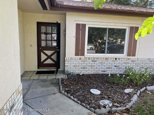 12801 Winding Way, Hudson, FL 34667 - view of exterior entry featuring stucco siding and brick siding