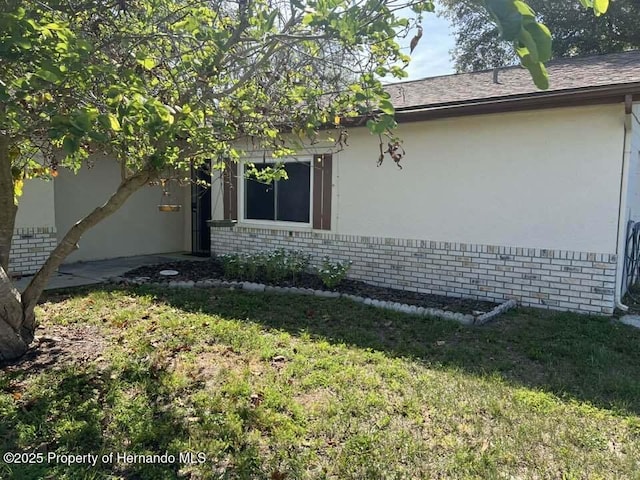 12801 Winding Way, Hudson, FL 34667 - view of side of property with brick siding, stucco siding, and a yard