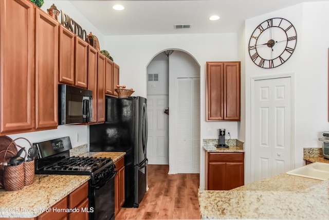 5233 Jennings Trl, Brooksville, FL 34601 - kitchen with black appliances, light wood finished floors, arched walkways, recessed lighting, and light stone countertops