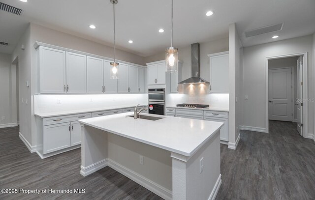 4056 Southern Valley Loop, Brooksville, FL 34601 - kitchen with wall chimney range hood, a sink, appliances with stainless steel finishes, backsplash, and a kitchen island with sink