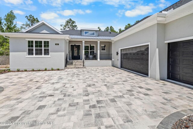 4522 Majestic Hills Loop, Brooksville, FL 34601 - view of front of house with covered porch, stucco siding, an attached garage, decorative driveway, and a standing seam roof