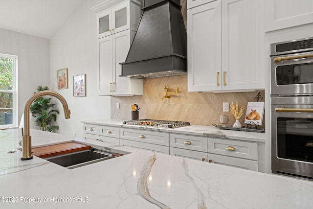 4522 Majestic Hills Loop, Brooksville, FL 34601 - kitchen featuring premium range hood, appliances with stainless steel finishes, tasteful backsplash, white cabinetry, and glass insert cabinets