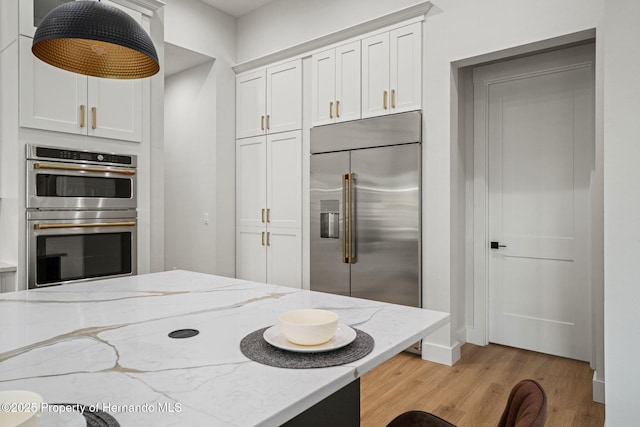 4522 Majestic Hills Loop, Brooksville, FL 34601 - kitchen featuring stainless steel appliances, light wood finished floors, white cabinetry, and light stone countertops