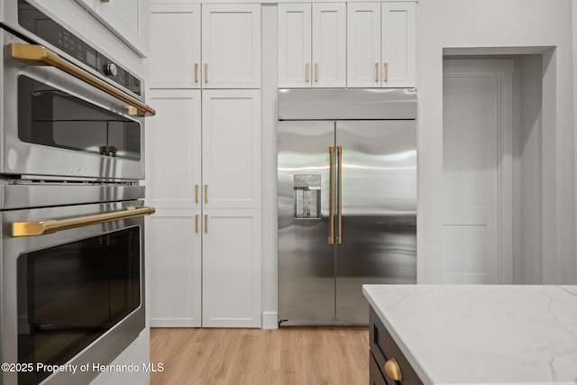 4522 Majestic Hills Loop, Brooksville, FL 34601 - kitchen with appliances with stainless steel finishes, light wood-type flooring, light stone counters, and white cabinets