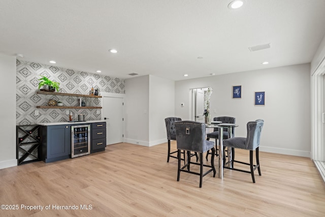 4522 Majestic Hills Loop, Brooksville, FL 34601 - dining space with wine cooler, a bar, an accent wall, recessed lighting, and light wood-style floors