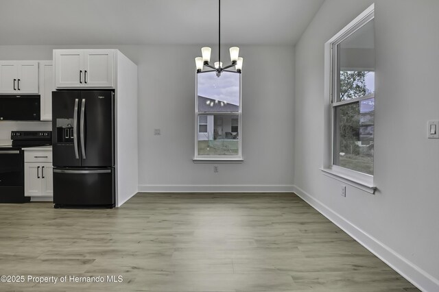 1080 Dunlap Ave, Spring Hill, FL 34609 - kitchen with black appliances, a chandelier, white cabinets, light wood-style floors, and baseboards