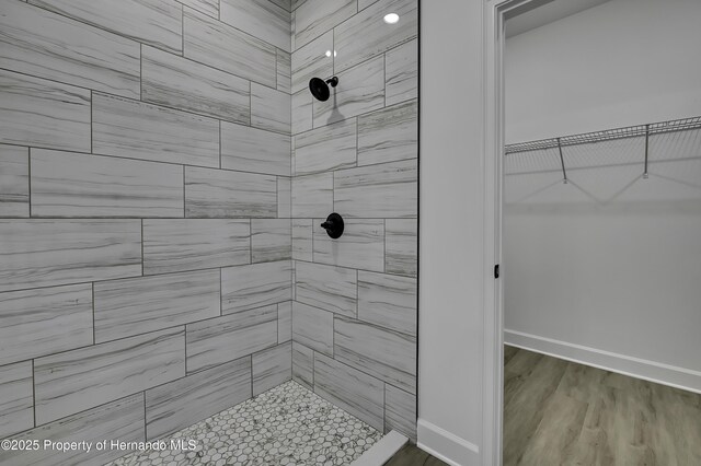 1080 Dunlap Ave, Spring Hill, FL 34609 - bathroom with a tile shower, baseboards, wood finished floors, and a spacious closet