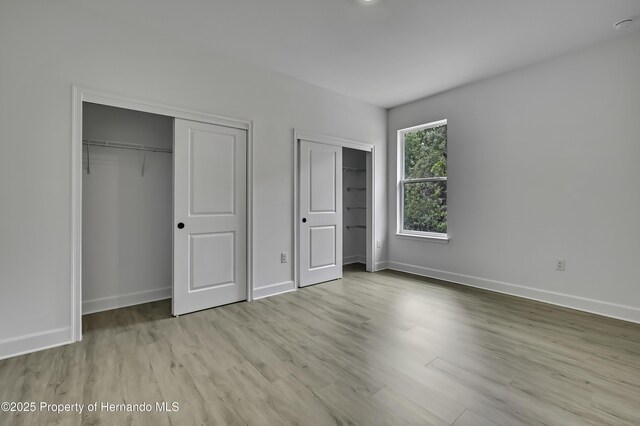1080 Dunlap Ave, Spring Hill, FL 34609 - unfurnished bedroom with two closets, wood finished floors, and baseboards
