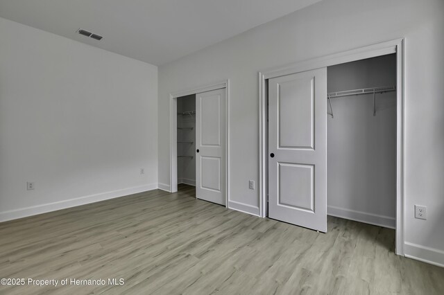 1080 Dunlap Ave, Spring Hill, FL 34609 - unfurnished bedroom featuring multiple closets, light wood finished floors, and baseboards