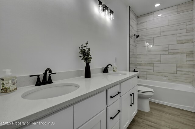 1080 Dunlap Ave, Spring Hill, FL 34609 - bathroom featuring double vanity, toilet, bathtub / shower combination, wood finished floors, and recessed lighting