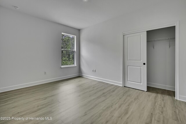 1080 Dunlap Ave, Spring Hill, FL 34609 - unfurnished bedroom with wood finished floors, baseboards, and a closet