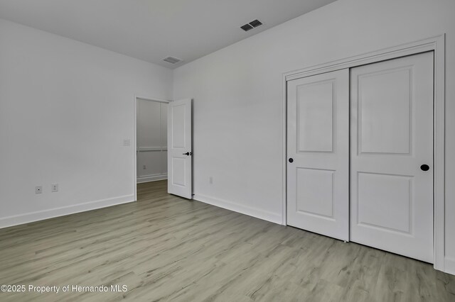 1080 Dunlap Ave, Spring Hill, FL 34609 - unfurnished bedroom featuring light wood-style floors, baseboards, and a closet