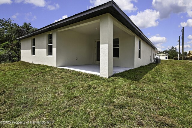 1080 Dunlap Ave, Spring Hill, FL 34609 - back of house featuring stucco siding, a patio, a yard, and central air condition unit
