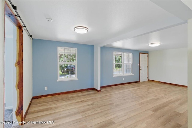 12301 Cedar St, Cedar Key, FL 32625 - empty room featuring a barn door, light wood-style floors, and baseboards