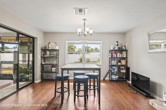 1038 Shenandoah Ln, Spring Hill, FL 34606 - dining area with wood finished floors, a chandelier, a textured ceiling, and baseboards