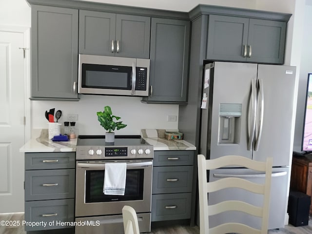 4983 Cedarbrook Ln, Hernando Beach, FL 34607 - kitchen with stainless steel appliances, gray cabinets, and wood finished floors