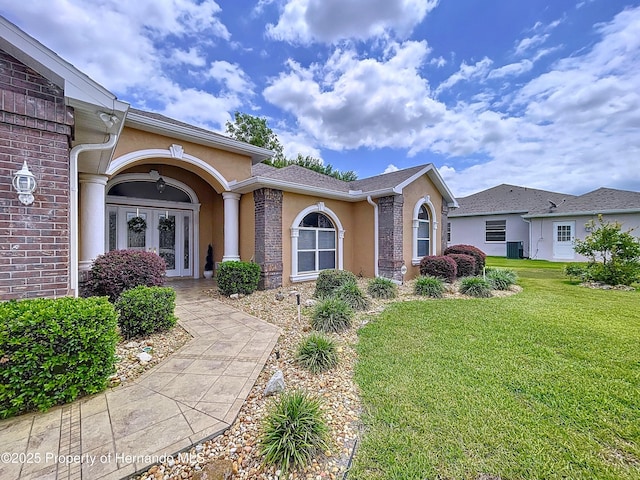 13417 Whitehaven Ct, Spring Hill, FL 34609 - view of front facade featuring french doors, a front lawn, and stucco siding