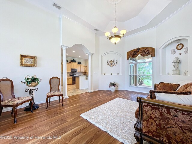 13417 Whitehaven Ct, Spring Hill, FL 34609 - living room featuring decorative columns, light wood finished floors, baseboards, a high ceiling, and arched walkways