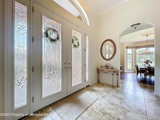 13417 Whitehaven Ct, Spring Hill, FL 34609 - entrance foyer featuring arched walkways, french doors, a chandelier, and baseboards