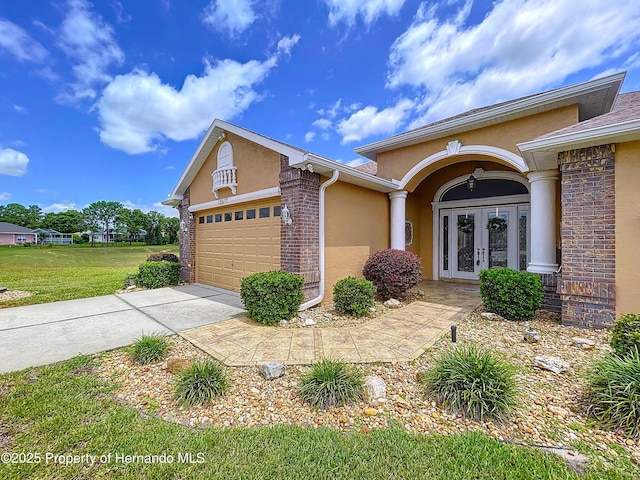 13417 Whitehaven Ct, Spring Hill, FL 34609 - view of front of home featuring french doors, stucco siding, an attached garage, a front yard, and concrete driveway