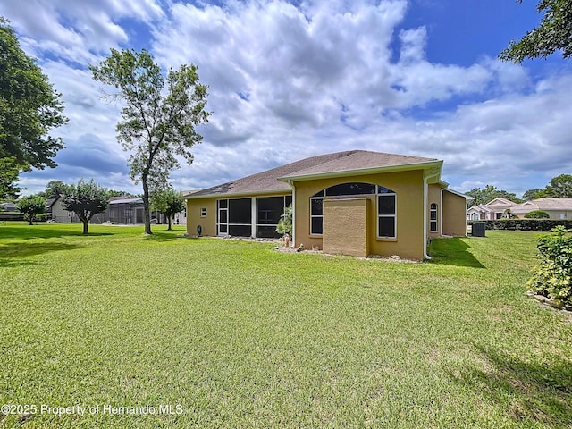 13417 Whitehaven Ct, Spring Hill, FL 34609 - rear view of house with stucco siding, a yard, a sunroom, and central AC