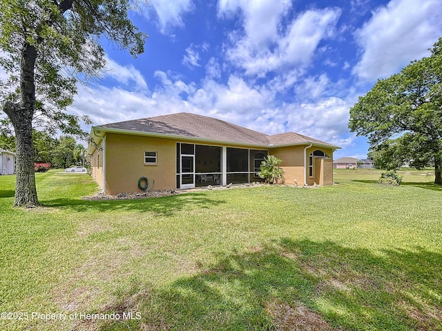 13417 Whitehaven Ct, Spring Hill, FL 34609 - back of property with stucco siding, a lawn, and a sunroom