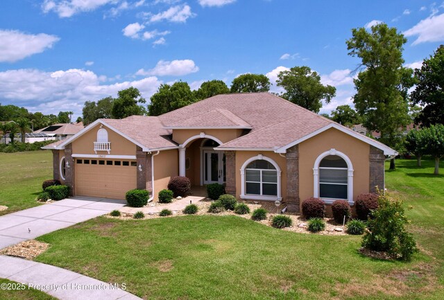 13417 Whitehaven Ct, Spring Hill, FL 34609 - mediterranean / spanish-style house featuring an attached garage, a front lawn, a shingled roof, driveway, and stucco siding