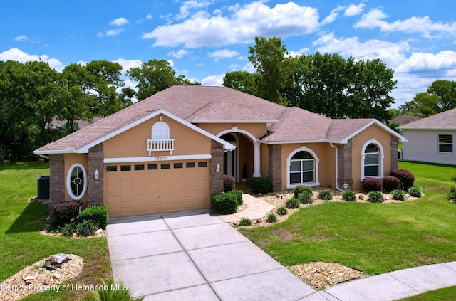 13417 Whitehaven Ct, Spring Hill, FL 34609 - view of front of home featuring cooling unit, a garage, a front yard, driveway, and stucco siding