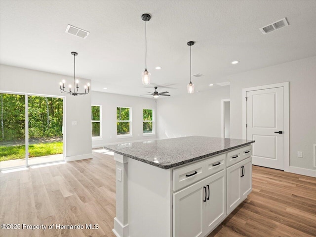 14448 Chimney Swift Rd, Weeki Wachee, FL 34614 - kitchen with light wood-style floors, ceiling fan, baseboards, a center island, and white cabinets