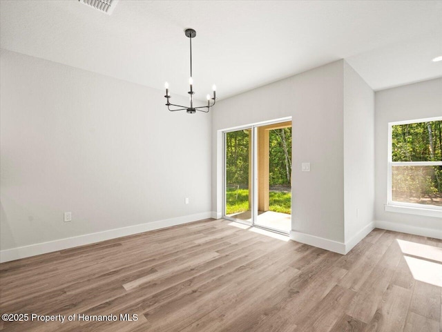 14448 Chimney Swift Rd, Weeki Wachee, FL 34614 - empty room featuring healthy amount of natural light, a chandelier, light wood-type flooring, and baseboards