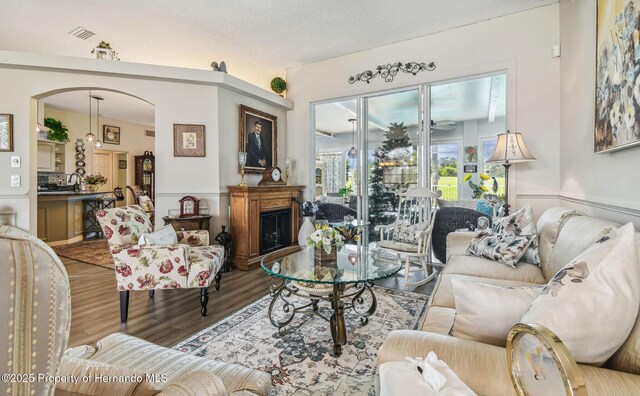 18223 Nestlebranch Ct, Hudson, FL 34667 - living room with wood finished floors, arched walkways, a wainscoted wall, and a fireplace