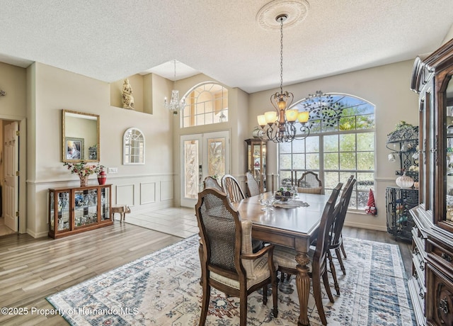 18223 Nestlebranch Ct, Hudson, FL 34667 - dining area with a chandelier, a textured ceiling, a wainscoted wall, a decorative wall, and wood finished floors
