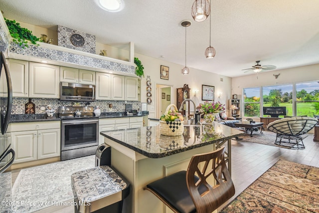 18223 Nestlebranch Ct, Hudson, FL 34667 - kitchen with appliances with stainless steel finishes, a ceiling fan, decorative backsplash, open floor plan, and a kitchen breakfast bar
