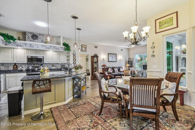 18223 Nestlebranch Ct, Hudson, FL 34667 - dining room with a chandelier, wood finished floors, and a textured ceiling