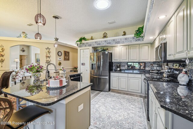 18223 Nestlebranch Ct, Hudson, FL 34667 - kitchen with appliances with stainless steel finishes, a sink, a textured ceiling, a breakfast bar, and decorative light fixtures
