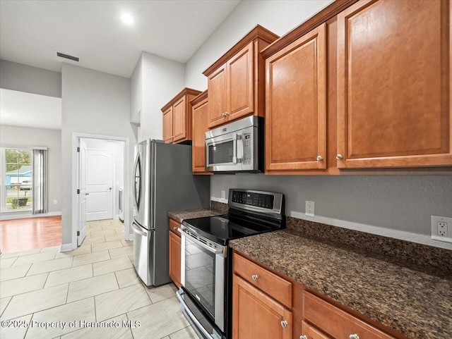 12167 Bath St, Spring Hill, FL 34609 - kitchen featuring stainless steel appliances, brown cabinetry, and dark stone counters