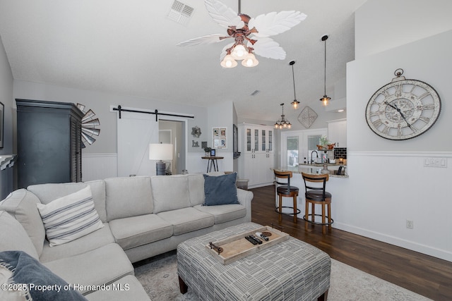 1049 Larkin Rd, Spring Hill, FL 34608 - living area with a barn door, dark wood-style flooring, wainscoting, ceiling fan, and lofted ceiling