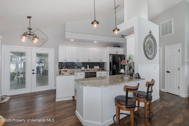 1049 Larkin Rd, Spring Hill, FL 34608 - kitchen with black fridge with ice dispenser, lofted ceiling, dishwasher, white cabinets, and tasteful backsplash