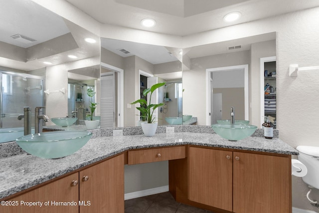 14031 Hexam Rd, Brooksville, FL 34613 - bathroom with double vanity, a stall shower, recessed lighting, tile patterned flooring, and toilet