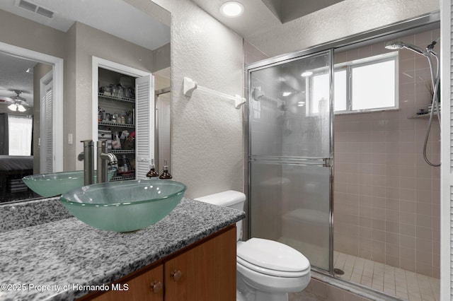 14031 Hexam Rd, Brooksville, FL 34613 - full bathroom with a textured wall, vanity, a stall shower, toilet, and a ceiling fan