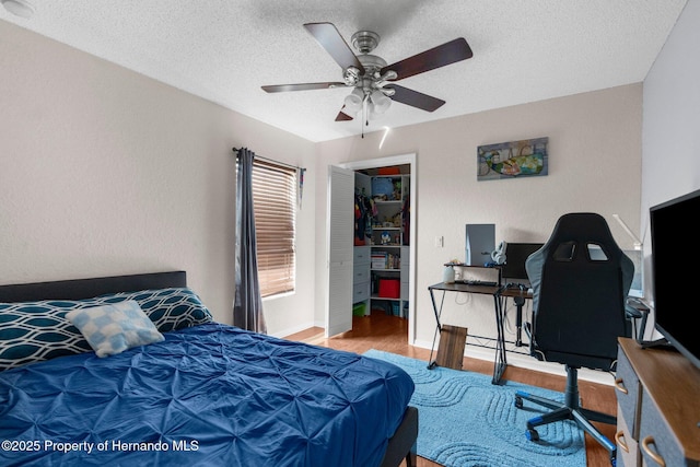 14031 Hexam Rd, Brooksville, FL 34613 - bedroom featuring wood finished floors, a desk, a textured ceiling, a ceiling fan, and a walk in closet